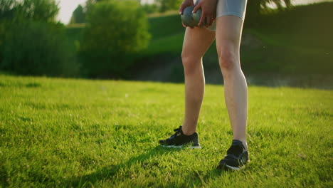 Close-up-of-a-squat-woman's-leg-in-a-park-on-grass-with-dumbbells